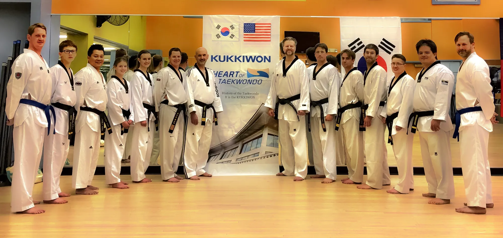 Black belts lined up in front of a Kukkiwon banner